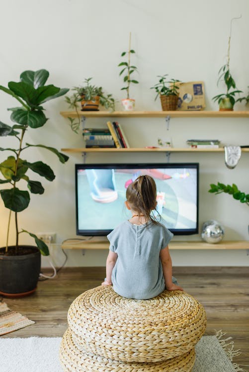 Kind sitzt vorm Fernseher und guckt TV